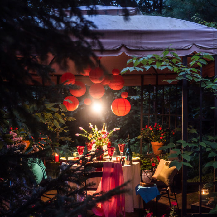 Red paper lanterns hanging inside a gazebo with the light on