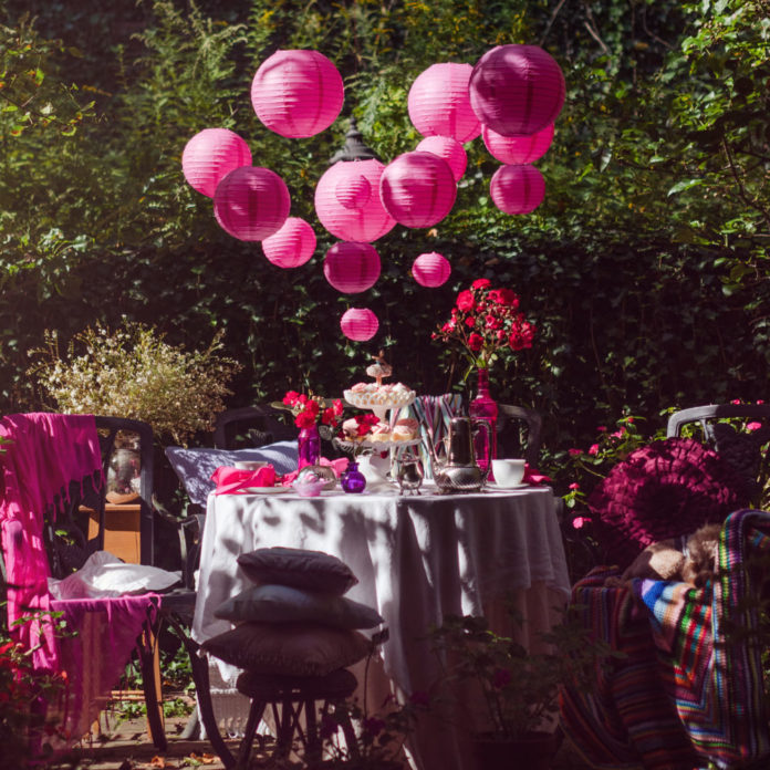 Hot pink paper lanterns hanging above an outdoor party table