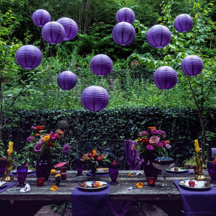 Purple paper lanterns hanging above an outdoor party table