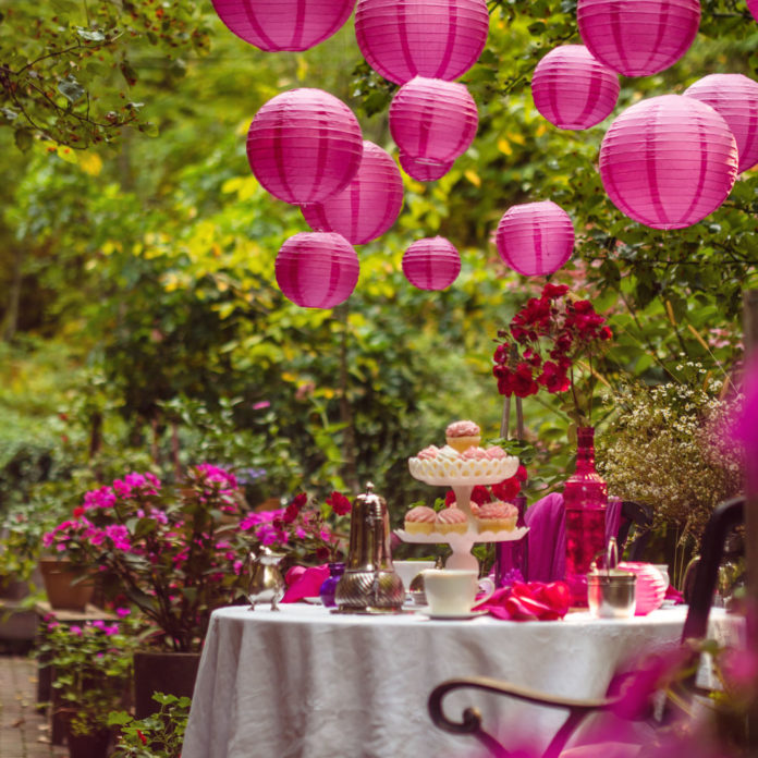 Hot pink paper lanterns hanging above an outdoor party table